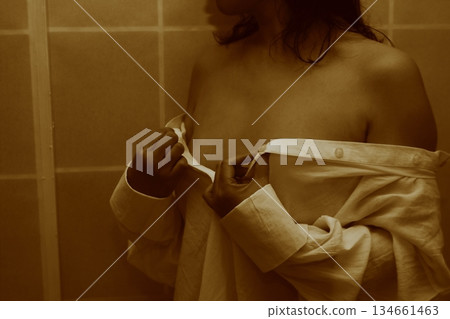 一名成年女性正在脫掉一件白襯衫 134661463