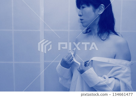 一名成年女性正在脫掉一件白襯衫 134661477