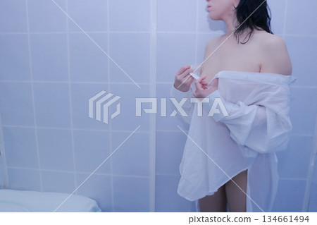 一名成年女性正在脫掉一件白襯衫 134661494