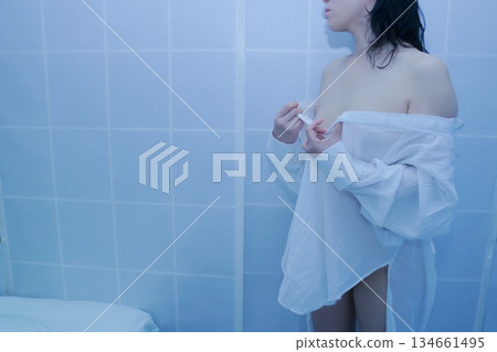 一名成年女性正在脫掉一件白襯衫 134661495