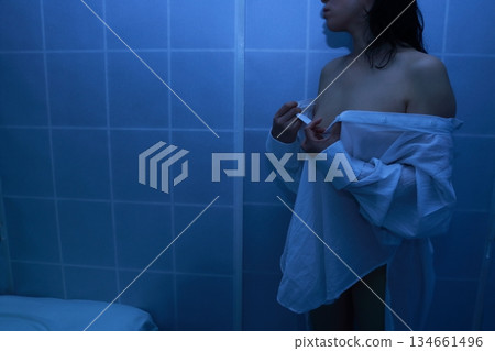 一名成年女性正在脫掉一件白襯衫 一名成年女性正在脫掉一件白襯衫 134661496