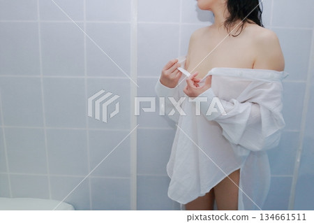 一名成年女性正在脫掉一件白襯衫 一名成年女性正在脫掉一件白襯衫 134661511