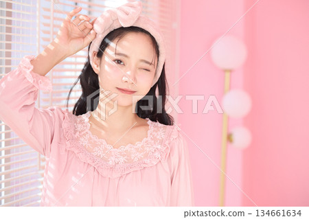 Beauty portrait of a young woman standing by the window in a pink room 134661634