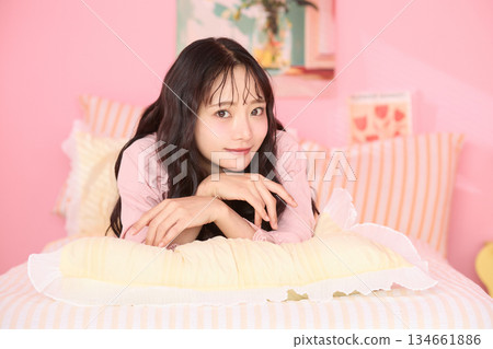 Cute portrait of a young woman relaxing in her colorful bedroom 134661886
