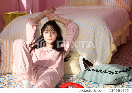 Cute portrait of a young woman relaxing in her colorful bedroom 134661895