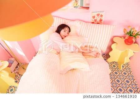 Cute portrait of a young woman relaxing in her colorful bedroom Cute portrait of a young woman relaxing in her colorful bedroom 134661910