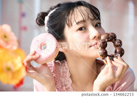 Portrait of a cute woman eating a donut in a colorful room Portrait of a cute woman eating a donut in a colorful room 134662253