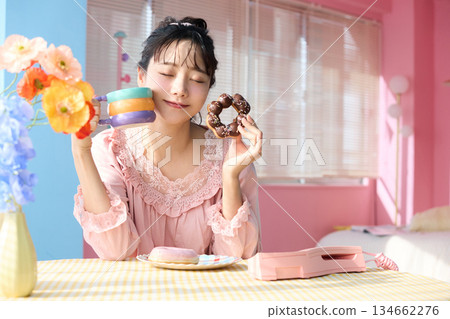 Portrait of a cute woman eating a donut in a colorful room 134662276