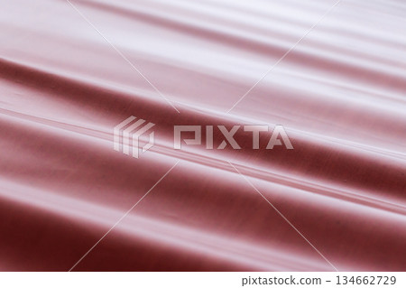 Red industrial fabric cascades in smooth waves, creating glossy background 134662729