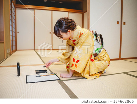 一位身著和服的年輕女子正在日式房間練習書法。 134662866
