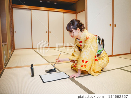 A young woman in a kimono practicing calligraphy in a Japanese-style room 134662867
