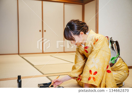 一位身著和服的年輕女子正在日式房間練習書法。 一位身著和服的年輕女子正在日式房間練習書法。 134662870