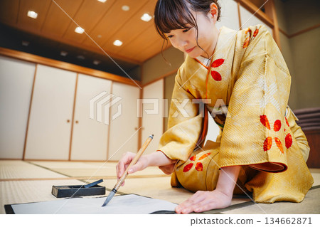 A young woman in a kimono practicing calligraphy in a Japanese-style room A young woman in a kimono practicing calligraphy in a Japanese-style room 134662871