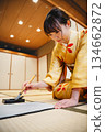 一位身著和服的年輕女子正在日式房間練習書法。 134662872