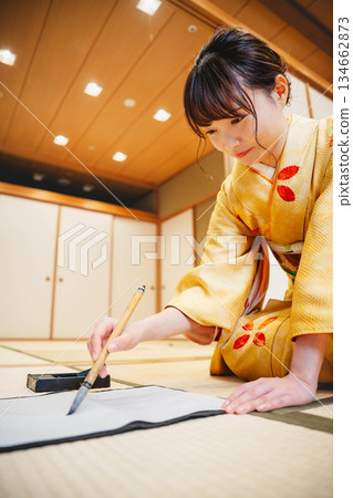 A young woman in a kimono practicing calligraphy in a Japanese-style room A young woman in a kimono practicing calligraphy in a Japanese-style room 134662873