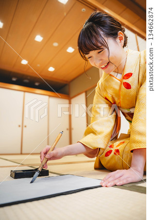 一位身著和服的年輕女子正在日式房間練習書法。 134662874