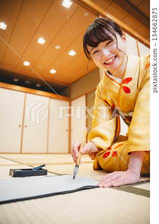 A young woman in a kimono practicing calligraphy in a Japanese-style room 134662875