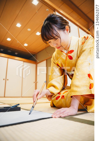A young woman in a kimono practicing calligraphy in a Japanese-style room 134662877