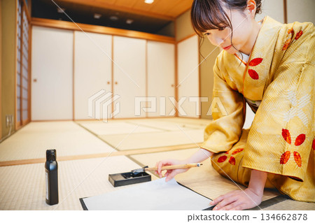 一位身著和服的年輕女子正在日式房間練習書法。 一位身著和服的年輕女子正在日式房間練習書法。 134662878