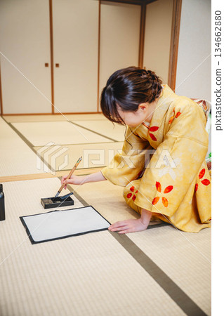A young woman in a kimono practicing calligraphy in a Japanese-style room A young woman in a kimono practicing calligraphy in a Japanese-style room 134662880