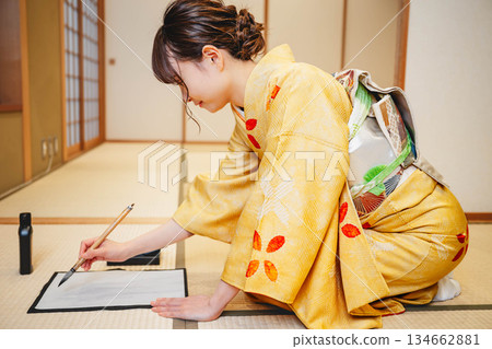 A young woman in a kimono practicing calligraphy in a Japanese-style room A young woman in a kimono practicing calligraphy in a Japanese-style room 134662881