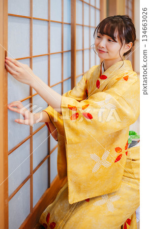 一位身穿和服的年輕女子正試圖打開障子門。 一位身穿和服的年輕女子正試圖打開障子門。 134663026