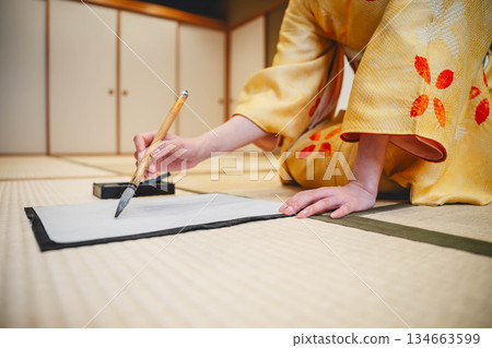 Hands practicing calligraphy in a kimono 134663599