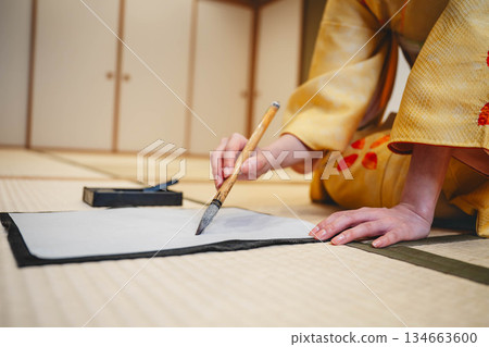 Hands practicing calligraphy in a kimono 134663600