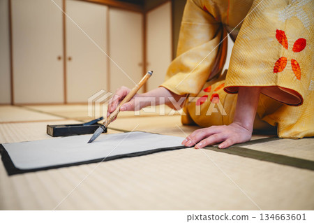 Hands practicing calligraphy in a kimono 134663601
