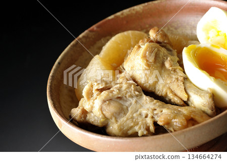 Chicken wings, radish, and egg stewed in sweet and spicy sauce photographed against a black background Chicken wings, radish, and egg stewed in sweet and spicy sauce photographed against a black background 134664274