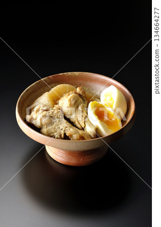 Chicken wings, radish, and egg stewed in sweet and spicy sauce photographed against a black background Chicken wings, radish, and egg stewed in sweet and spicy sauce photographed against a black background 134664277