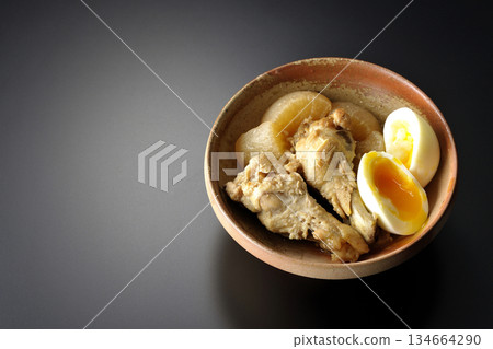 Chicken wings, radish, and egg stewed in sweet and spicy sauce photographed against a black background 134664290