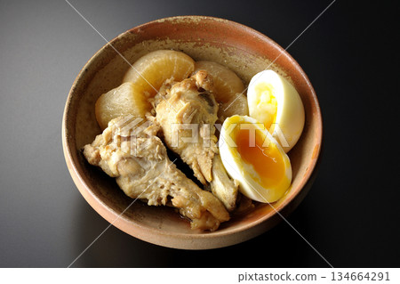 Chicken wings, radish, and egg stewed in sweet and spicy sauce photographed against a black background Chicken wings, radish, and egg stewed in sweet and spicy sauce photographed against a black background 134664291