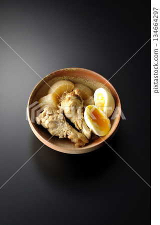 Chicken wings, radish, and egg stewed in sweet and spicy sauce photographed against a black background Chicken wings, radish, and egg stewed in sweet and spicy sauce photographed against a black background 134664297