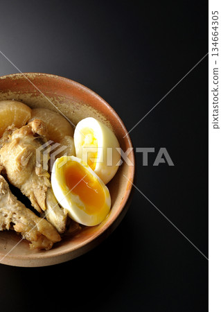 Chicken wings, radish, and egg stewed in sweet and spicy sauce photographed against a black background Chicken wings, radish, and egg stewed in sweet and spicy sauce photographed against a black background 134664305