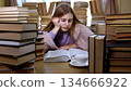 Tired girl in the library among many books 134666922