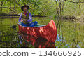 Cowboy in a canoe floats on the river in the forest 134666925