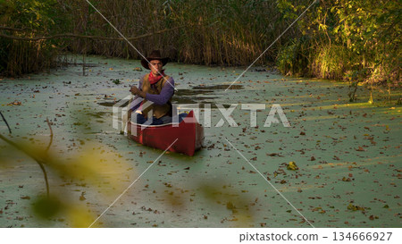 Cowboy in a canoe floats on the river Cowboy in a canoe floats on the river 134666927