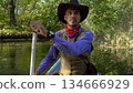 Cowboy in a canoe floats on the river in the forest 134666929