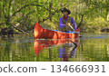 Cowboy in a canoe floats on the river in the forest 134666931