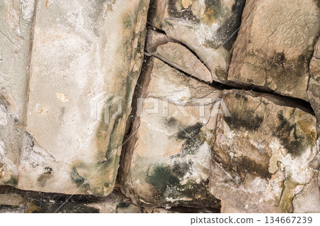 Close up texture background of cracked and weathered ancient stone wall blocks with green moss details in Cambodia temple Close up texture background of cracked and weathered ancient stone wall blocks with green moss details in Cambodia temple 134667239