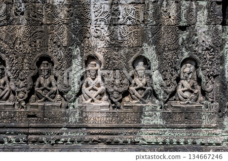 Intricate stone bas relief carvings of seated figures on ancient wall of terrace of leper king in angkor thom Intricate stone bas relief carvings of seated figures on ancient wall of terrace of leper king in angkor thom 134667246