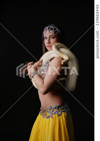 Woman performs dance holding a snake in a dark space during a live event Woman performs dance holding a snake in a dark space during a live event 134668448