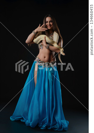 Woman dances with snake in a studio at night during a performance 134668455