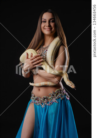 Woman dances with a snake in a dark setting showcasing movement and connection Woman dances with a snake in a dark setting showcasing movement and connection 134668456