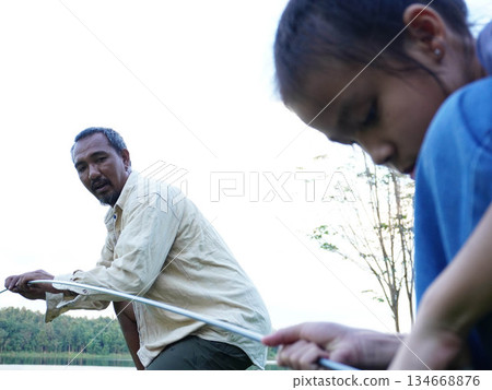 Father and Daughter Setting Up Camping Tent Together on Green Grass. 134668876