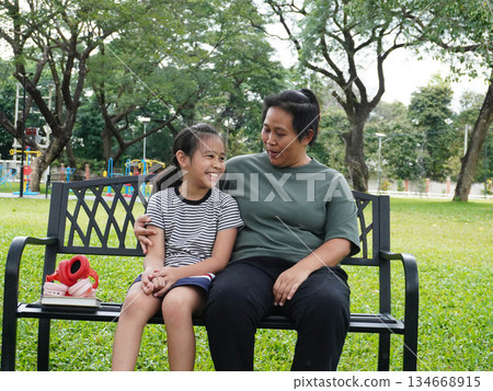 Mother and Daughter Relaxing on Park Bench with Music and Smartphone Mother and Daughter Relaxing on Park Bench with Music and Smartphone 134668915