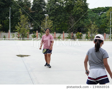 Mother and Daughter Playing Badminton on Outdoor Court Mother and Daughter Playing Badminton on Outdoor Court 134668916
