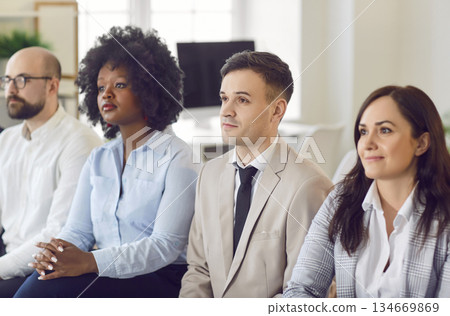 Group of business people sitting in a row on a meeting in office listening to their colleague 134669869