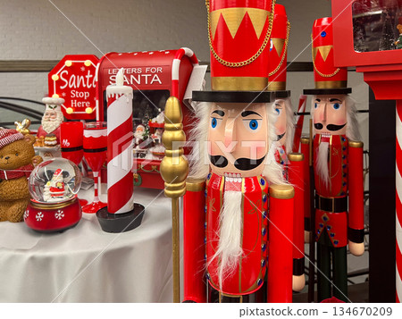 Classic red nutcracker figures standing among a festive display of traditional Christmas decorations, including a Santa mailbox and holiday ornaments, evoking seasonal joy Classic red nutcracker figures standing among a festive display of traditional Christmas decorations, including a Santa mailbox and holiday ornaments, evoking seasonal joy 134670209